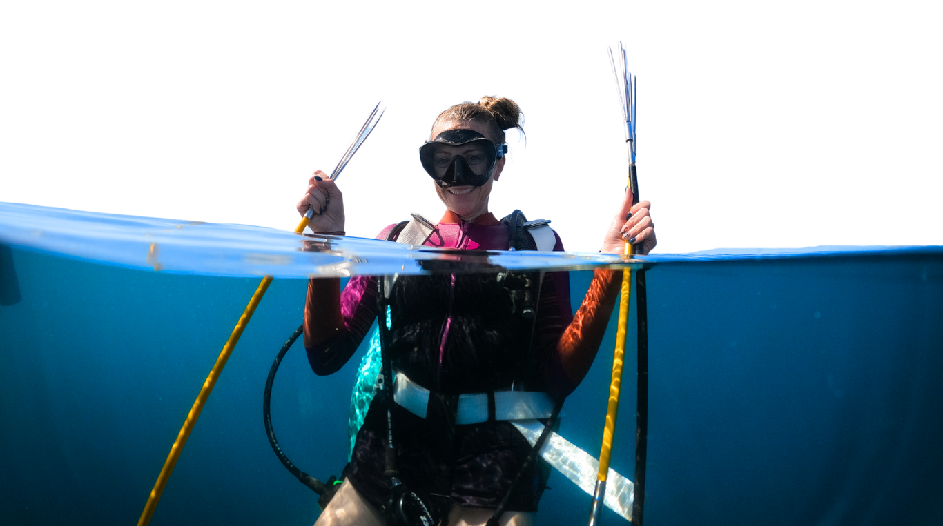 FINS Belize diver holding lionfish spears to remove invasive lionfish from the ocean to make handcrafted lionfish jewelry and support ocean conservation